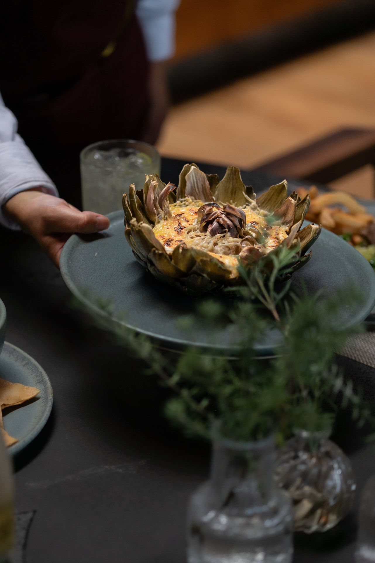 Alcachofa gratinada servida en vajilla artesanal, detalle gastronómico de la sobremesa
