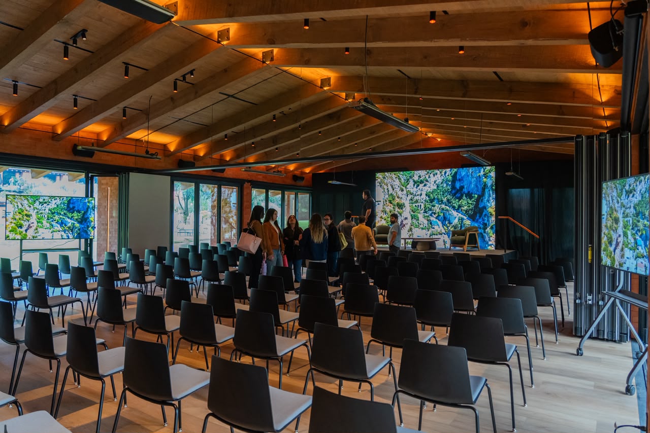 Vista interior de Salón Jardín montado para un evento, con techos de madera y ventanales al jardín
