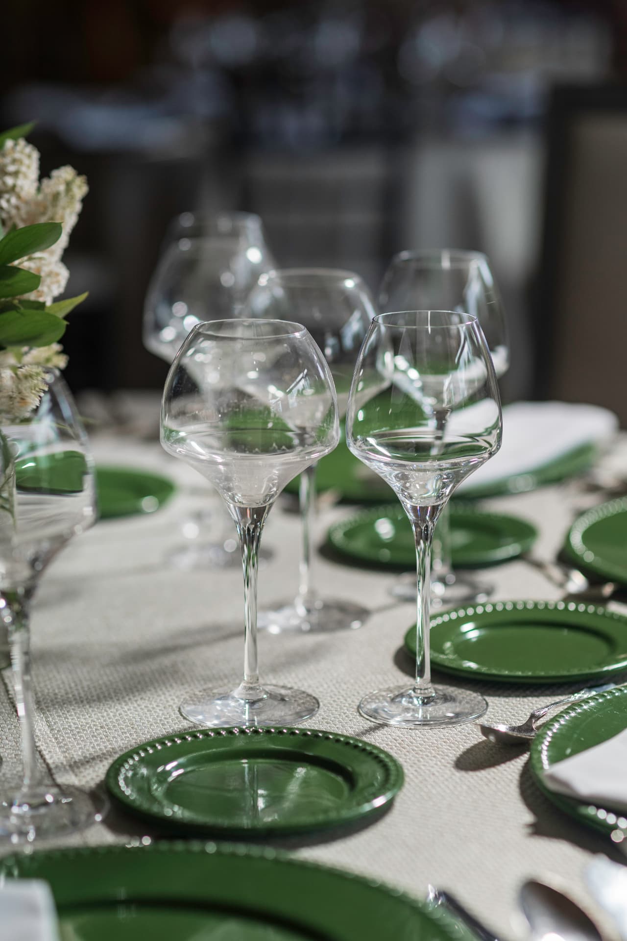 Montaje de mesa con cristalería, vajilla verde y detalles florales en Salón Jardín